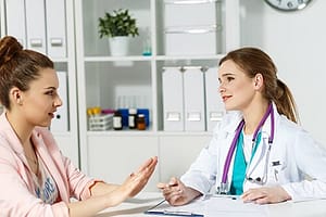 Female counselor and young woman at a table discussing dual diagnosis rehab.