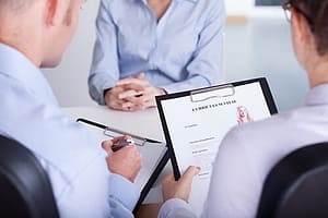 Two faceless clinicians conducting a substance abuse assessment with a third person.