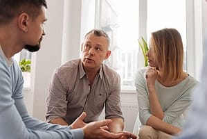 Three people in group at an alcoholic rehab center