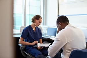 Intake counselor at an medical alcohol detox center talking to upset man