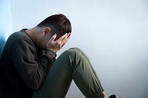 Man hiding face in hands dealing with the side effects of heroin use