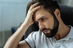 Distressed man with hand to forhead wants to know what is robotripping