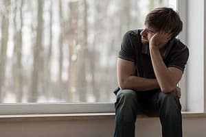 Guy on window seat staring out a window struggling with cocaine and alcohol addiction