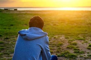 Person on beach contemplating relapse triggers and how to avoid them