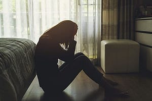 Depressed woman in dark bedroom needs mental health treatment therapy