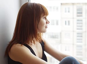 Woman looking out city window needs a fentanyl detox center