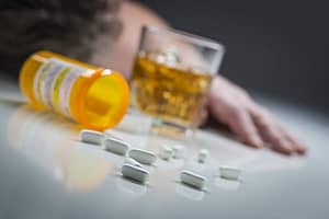 Picture of whiskey and pills on a table may mean a drug and alcohol addiction .