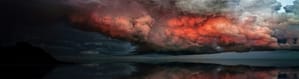 red-appearing storm clouds reflected over water