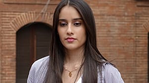 Dark haired young woman in front of brick wall deciding whether to attempt drug detox.