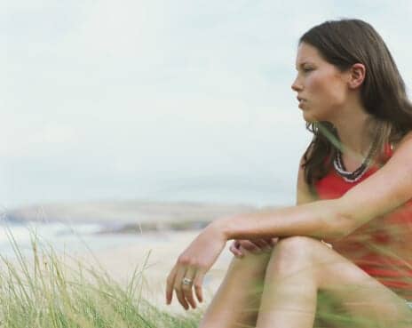 Woman sitting on the beach looking at the ocean