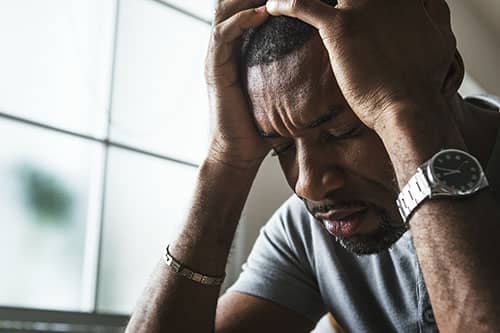 individual holding head in hands because of addiction