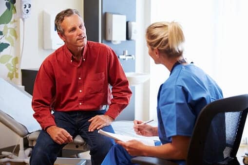 Patient And Female Doctor Have Consultation In Hospital Room