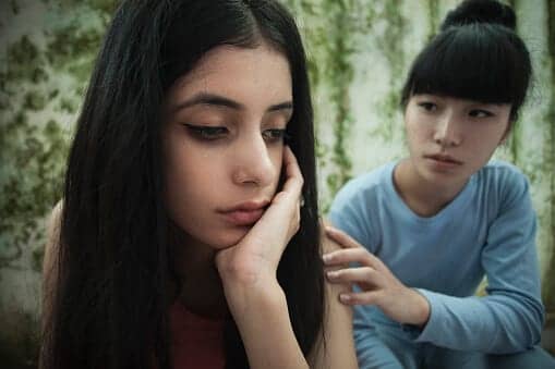 Young woman placing a hand on her friend's shoulder to console her