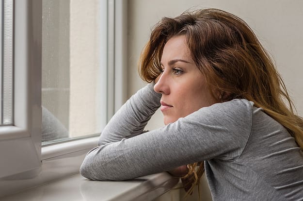 a woman stares out the window as she thinks about depression and addiction