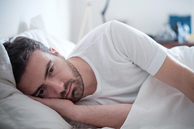 man laying in bed going through the most common cocaine withdrawal symptoms