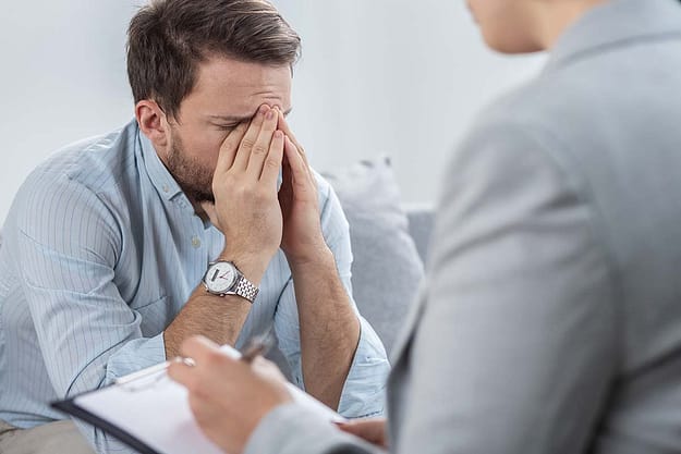 man with hands over his face consulting therapist about executive drug detox programs