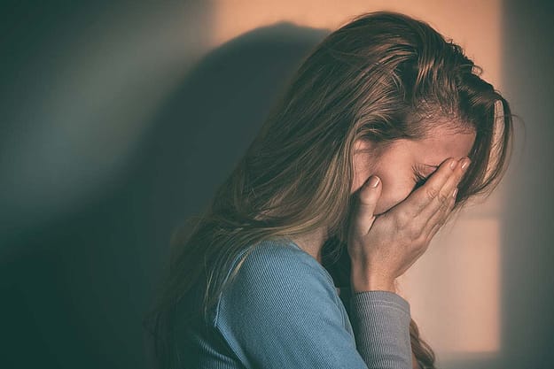 young woman covering her face from the disease of addiction