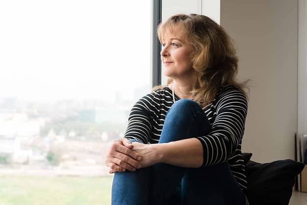 woman looking out the window of a drug and alcohol rehabilitation center