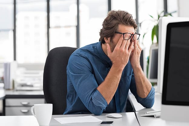 man rubbing face needing stress management techniques at work