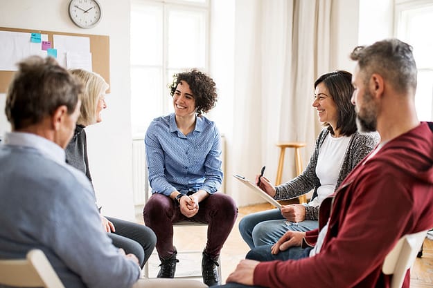 a group of people talk at a 12 step program of aa