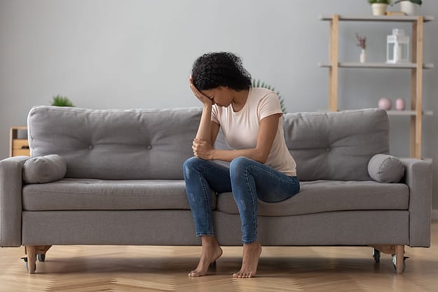 woman on couch with head in her hand from Side Effects of Xanax abuse