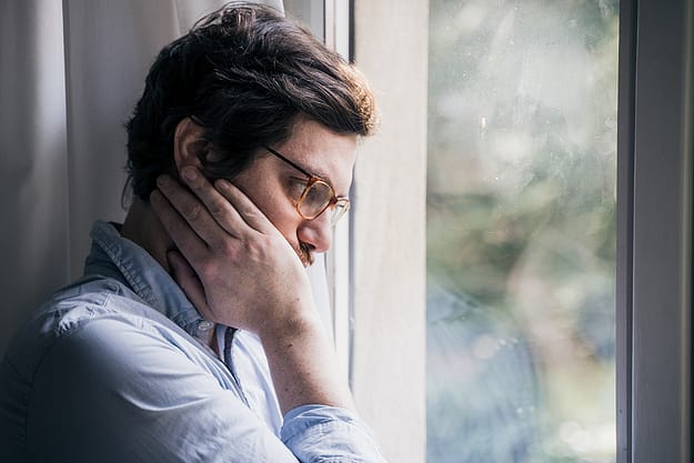 man looking out window concerned about how to fight drug cravings