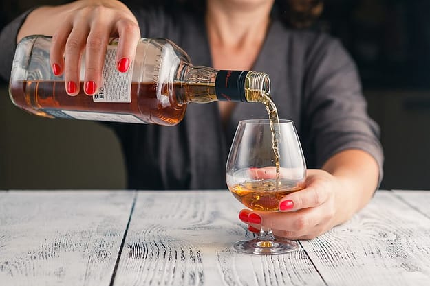 a person pours a drink ignoring Alcohol Awareness Month