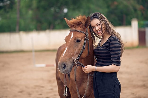 a woman smiles next to a horse thinking about the benefits of equine therapy