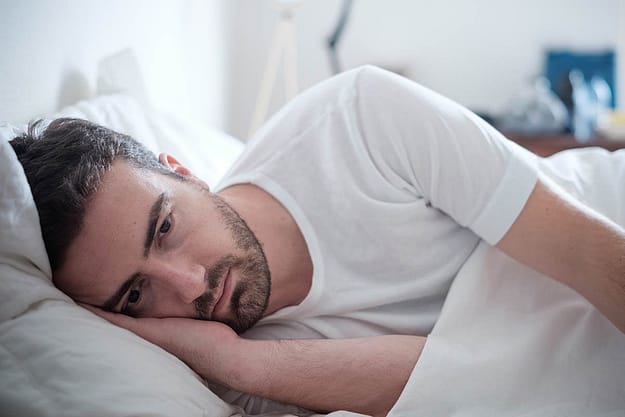 Man laying in bed wonders what is clinical depression