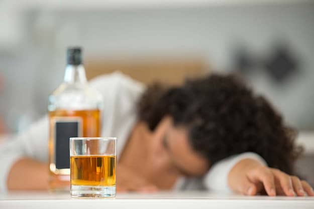 woman passed out next to whiskey showing the need for the alcohol rehab program in florida