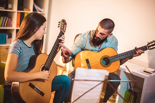 a teacher showing a young student a guitar note during Music Drug Rehab