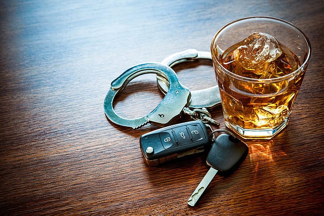 Car keys and glass of alcohol on table leads to the question of the difference between dui vs dwi