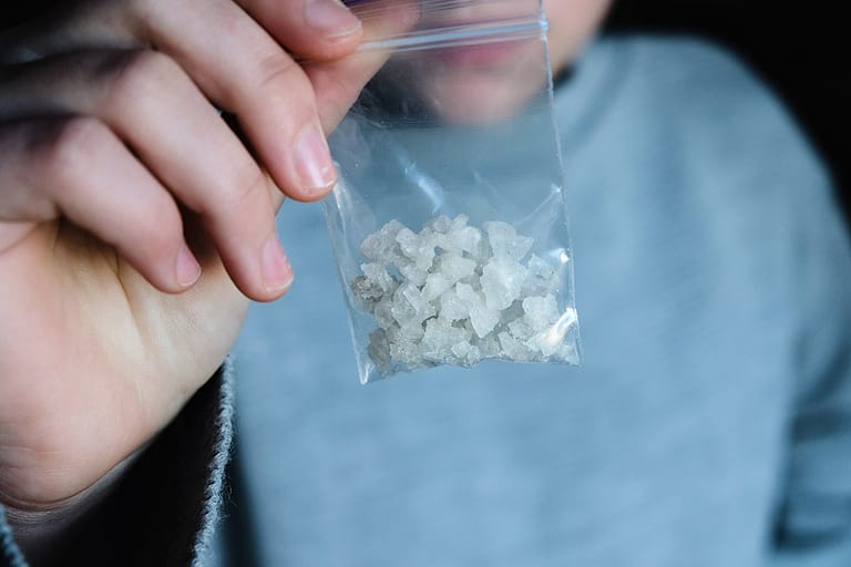 individual holding up a baggy of meth to show the effects of meth