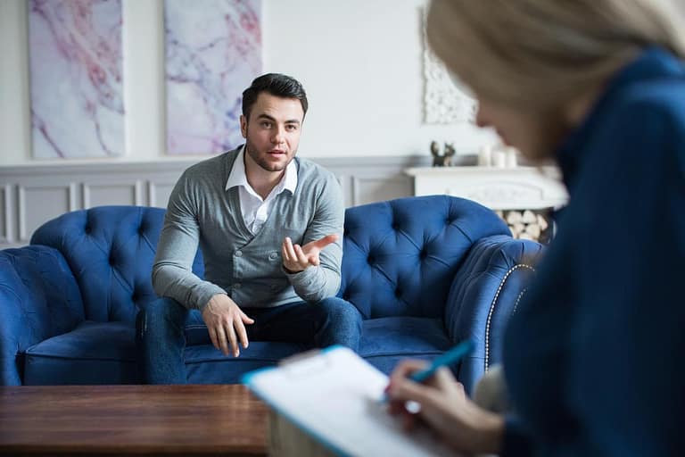Client sitting on couch talking to therapist during CBT session