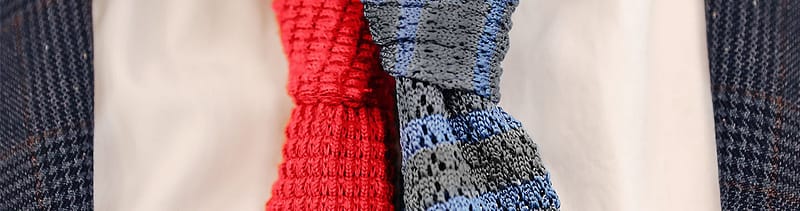 Two knitted ties, one solid red and one gray with blue stripes
