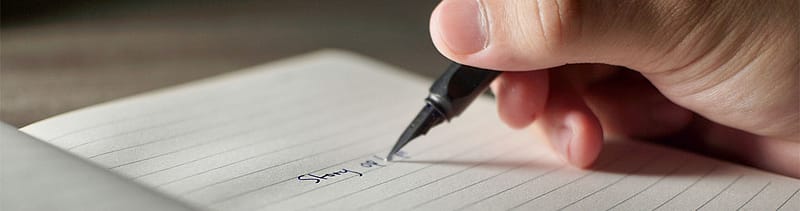 Close-up of someone writing a story by hand, representing how human-centered storytelling and authentic engagement help healthcare brands rebuild patient trust.