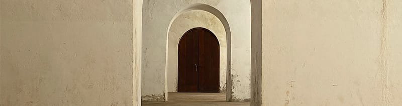 Architectural archway with a brown wooden door beyond