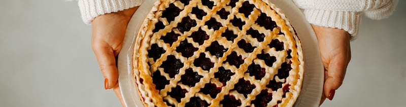 Two hands present a freshly baked apple pie, representing the concept in ‘Rethinking revenue’ that growth comes from expanding the pie, not dividing it differently