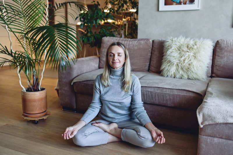 A woman in addiction recovery practicing self-care by meditating.