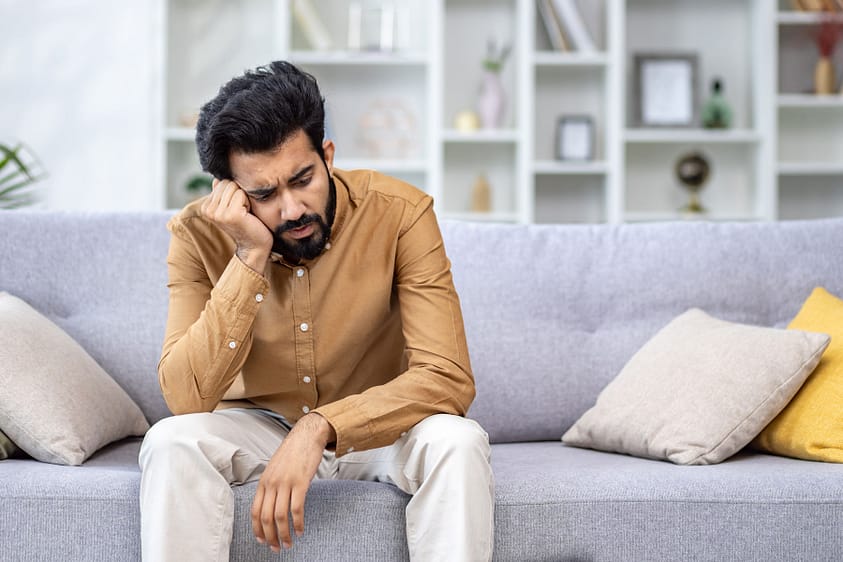 a man with crippling anxiety sits on his couch
