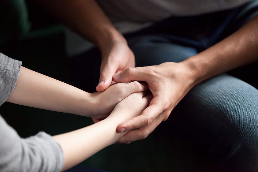 A couple holds hands in a moment of family support during addiction treatment.