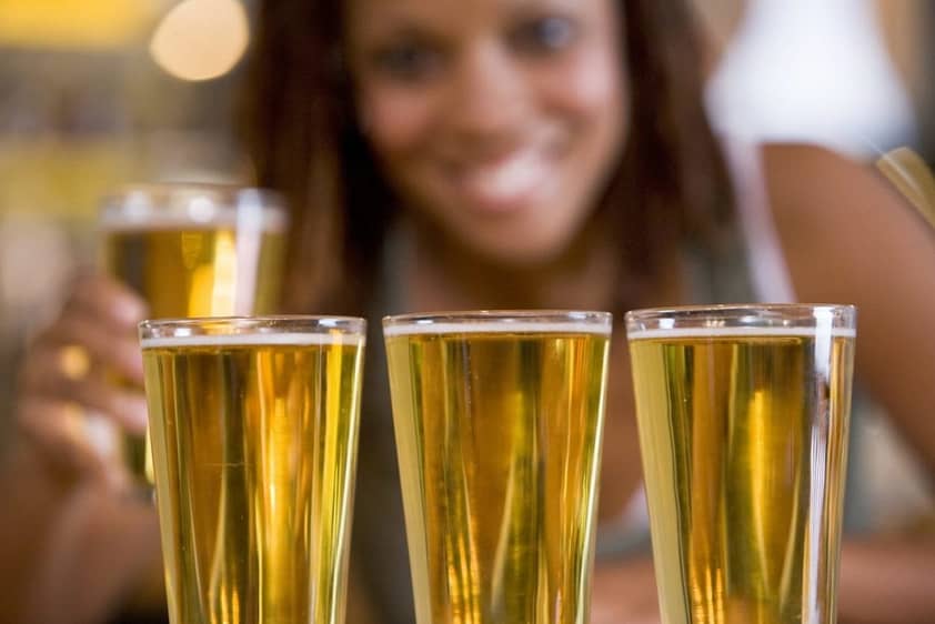 A woman with a row of beers experiences binge drinking effects.