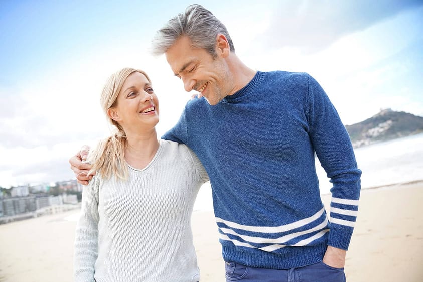 Middle-aged couple walks along the beach at a Florida heroin rehab center.