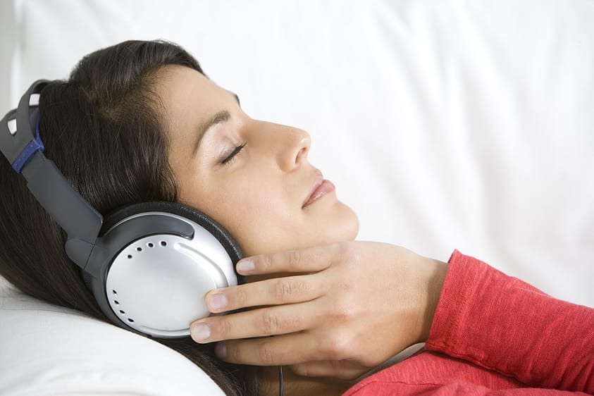 A woman wearing headphones achieves relaxation and other sound therapy benefits.