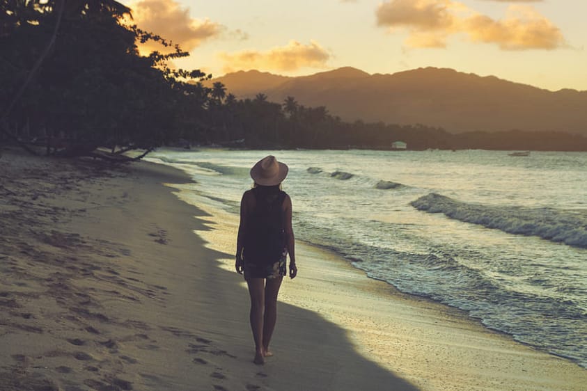 A woman in recovery walking on a beach at sunset