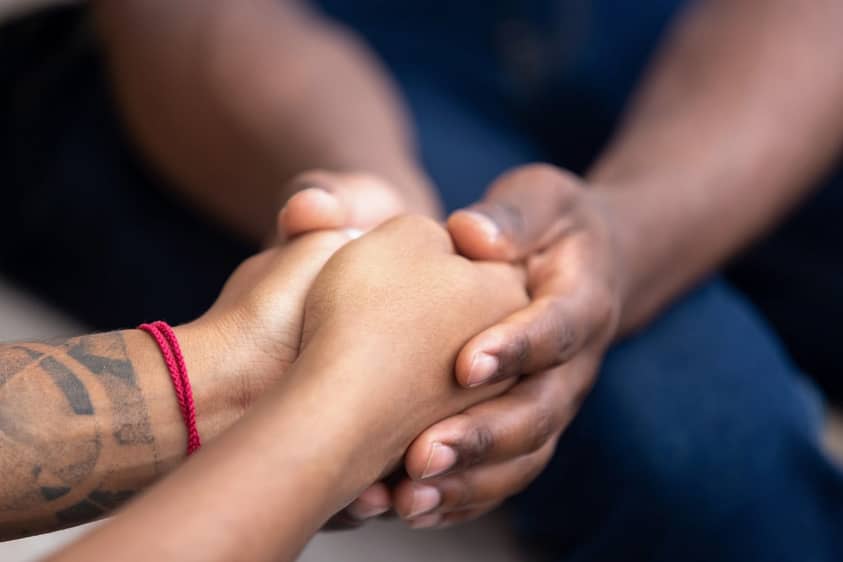 A man dating a recovering addict holds his partner's hands.
