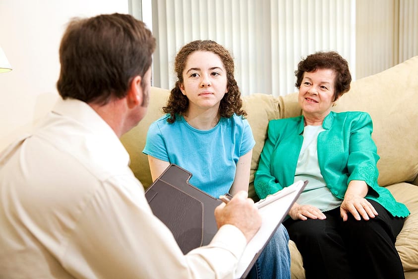 Mother sits on couch with daugther and discovering signs your child needs therapy