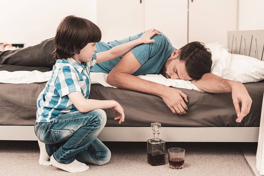 A son struggles to rouse his drunken father from sleep.