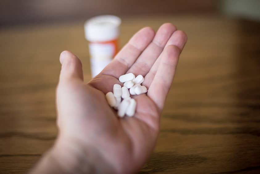 A hand holding a large amount of cyclobenzaprine pills.