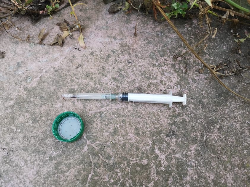 A heroin needle sits on the ground.